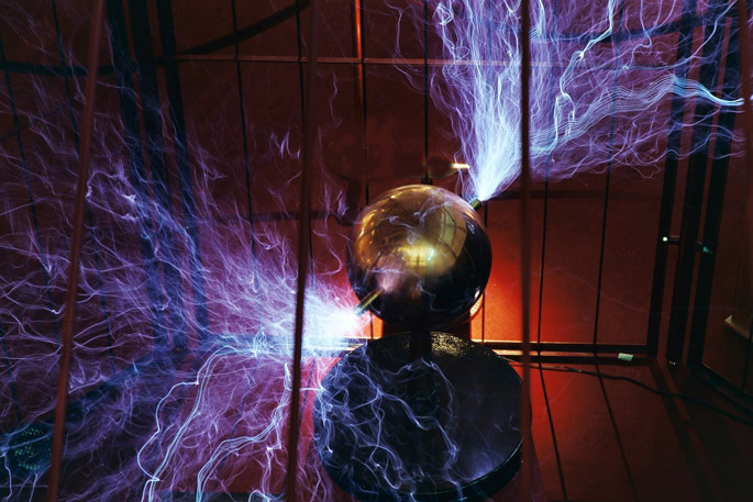 Metallic sphere devise with opposite protruding rods emitting bright thin blue waves in metal cage