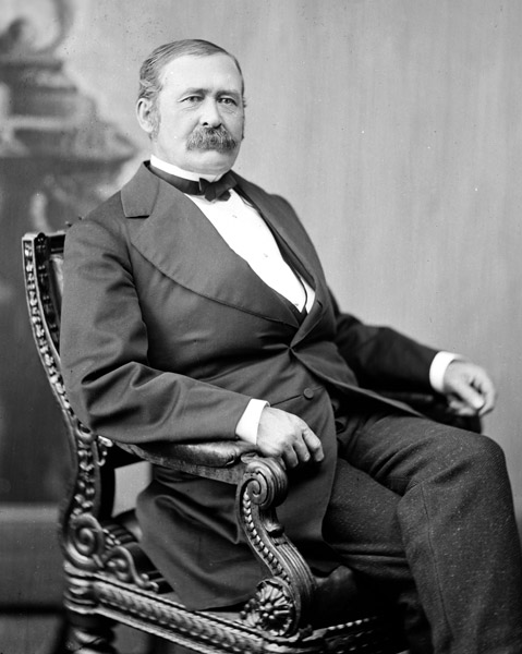 white man with mustache in suit sitting on chair