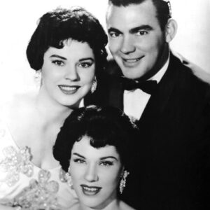 Portrait of white man in tuxedo and two white women in formal dresses and earrings