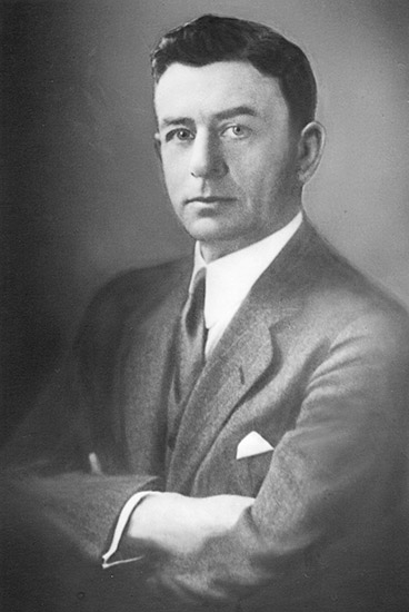 White man with arms crossed in suit and tie