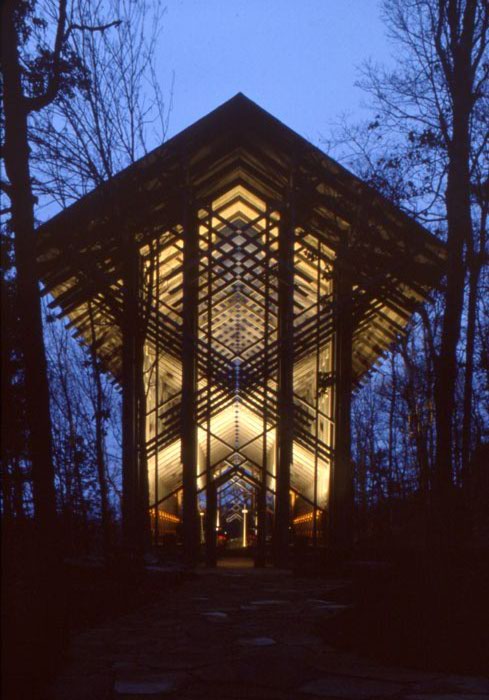 Lighted glass-walled chapel at night with trees