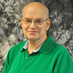 Bald white man with glasses smiling in green shirt