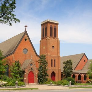 brick church with red doors, bell tower, and steeple