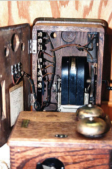 an opened crank telephone showing the inner mechanisms