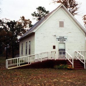 Rural wood frame building with gabled roof, stairs, ramp, "Tulip Community Building" sign