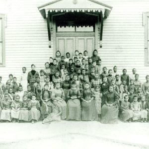 Group of African-American children and teachers outside a clapboard school house