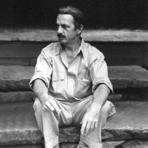 White man with mustache sitting on stone steps