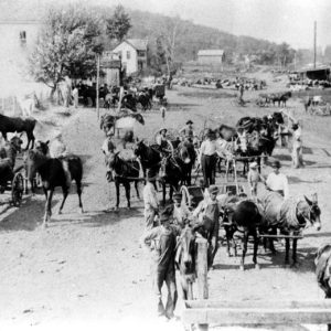 Group of people with buggies and on horseback on dirt road