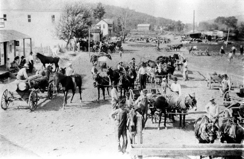 Group of people with buggies and on horseback on dirt road