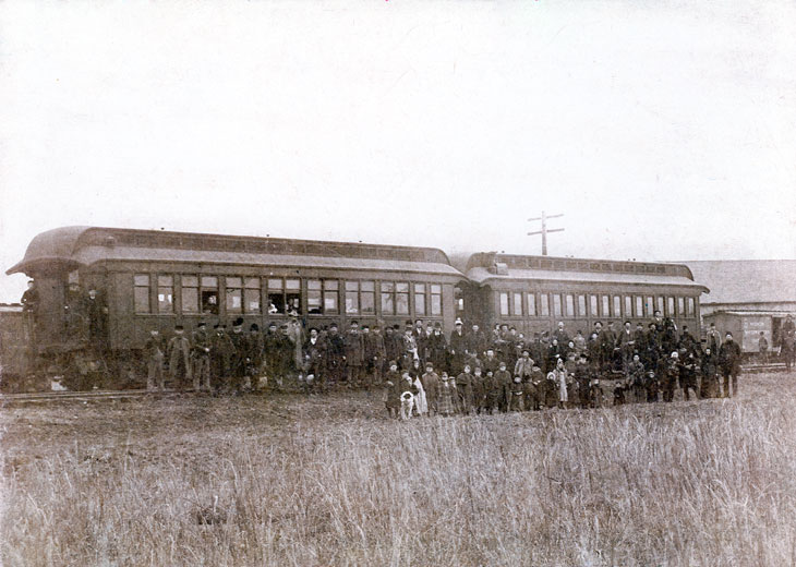 Group of people posing with train cars at depot