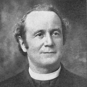 White man with sideburns in black suit and white priest's collar