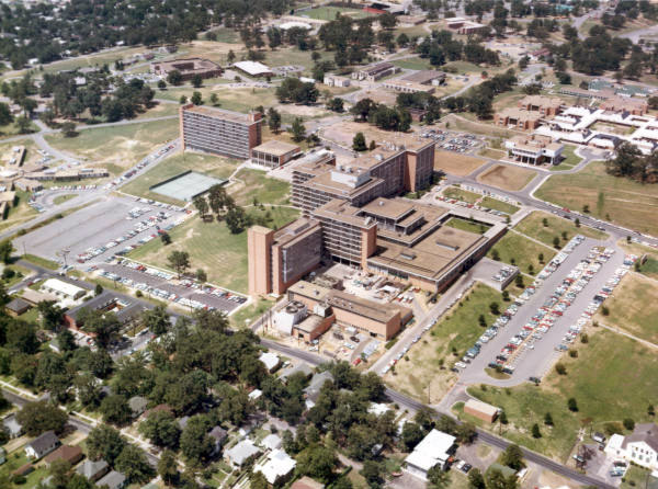 Campus of multistory buildings and outbuildings with parking lots and surrounding neighborhoods as seen from above