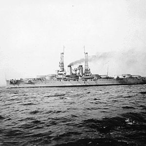 Battleship from distance with chimney smoke on choppy water