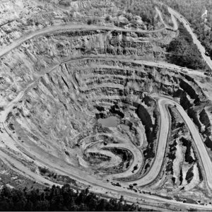 View looking down into an open pit mine with winding dirt roads and vehicles at the bottom