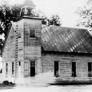 old black and white photo of church building with bell tower and trees