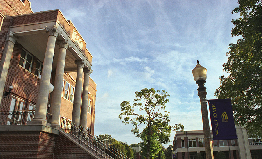 Multistory brick building with covered porch four columns and stairs on college campus