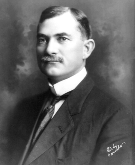 white man with mustache in suit and tie