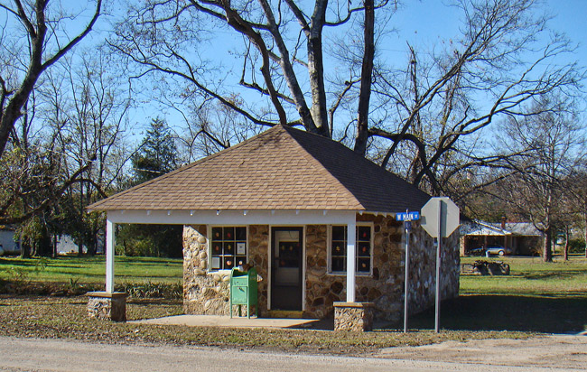 Small single-story stone building with covered entrance on street