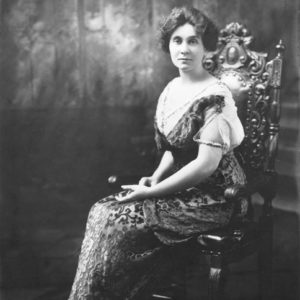 White woman in fancy dress sitting in an ornate wooden chair