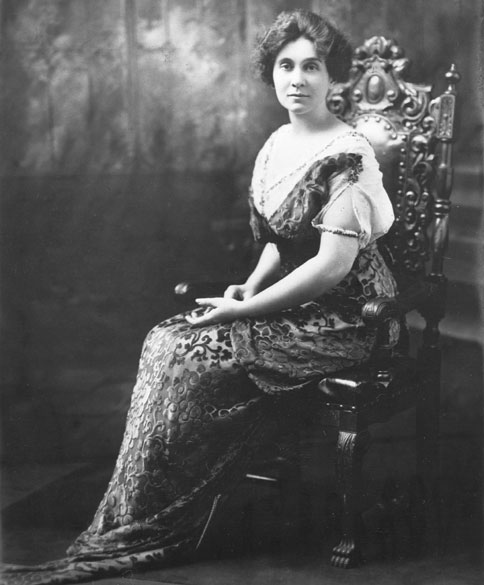 White woman in fancy dress sitting in an ornate wooden chair