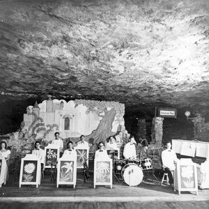 Musicians and instruments before backdrop on stage in cave