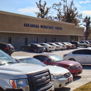 Parked cars outside single-story building with "Arkansas Workforce Center" in blue letters above the entrance