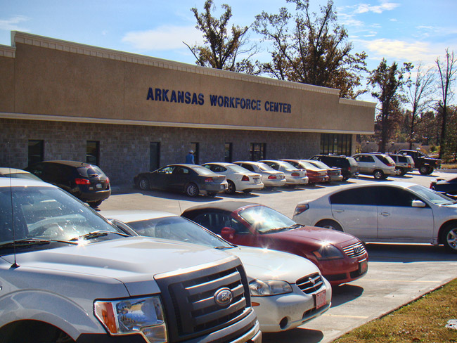 Parked cars outside single-story building with "Arkansas Workforce Center" in blue letters above the entrance