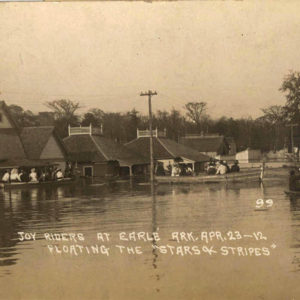 People in boats floating past flooded buildings