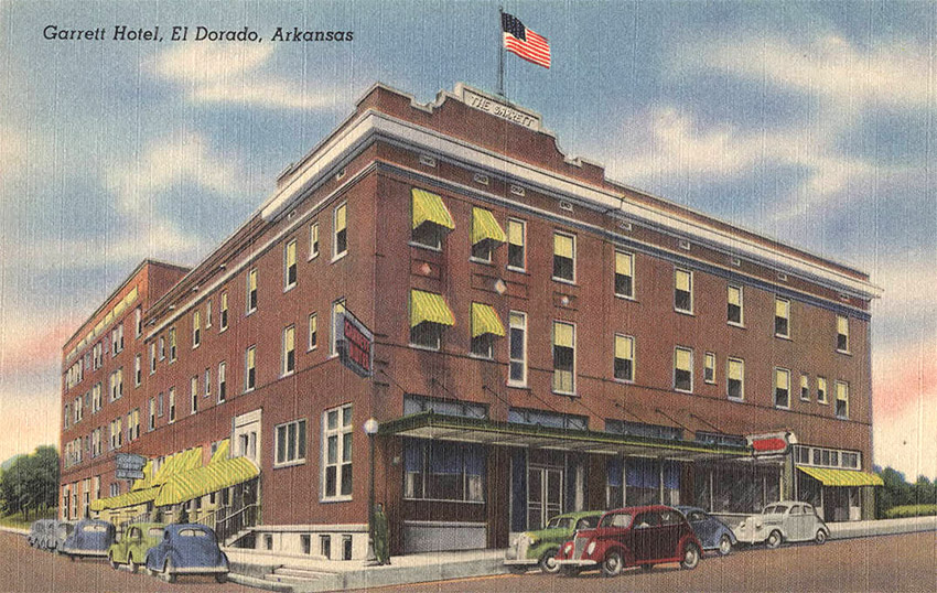Postcard featuring multistory brick hotel with cars parked on street