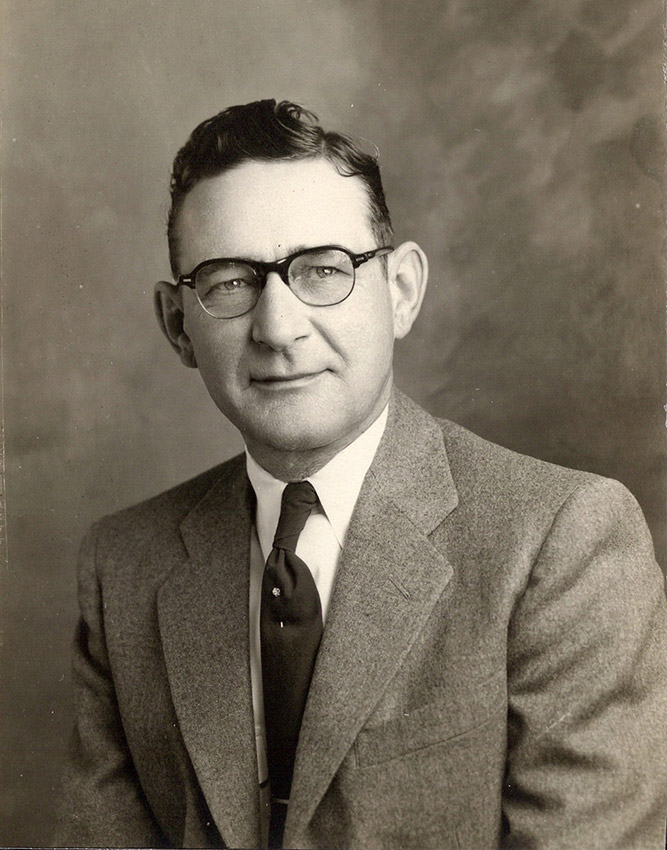 Portrait of white man in suit wearing black framed glasses