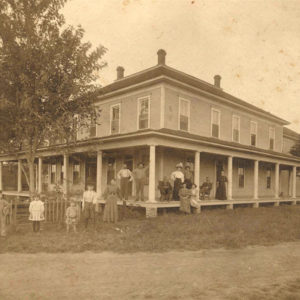 Two story building with people standing on wraparound porch