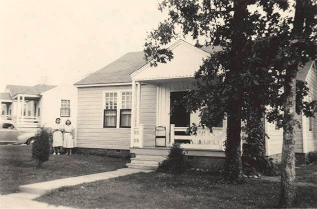 Two white women standing in yard between two white houses