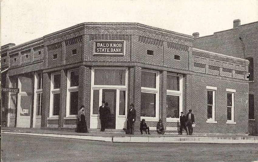 Single story brick building on corner with people standing on sidewalk
