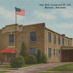 Two story blond brick building with red awning and American flag on pole