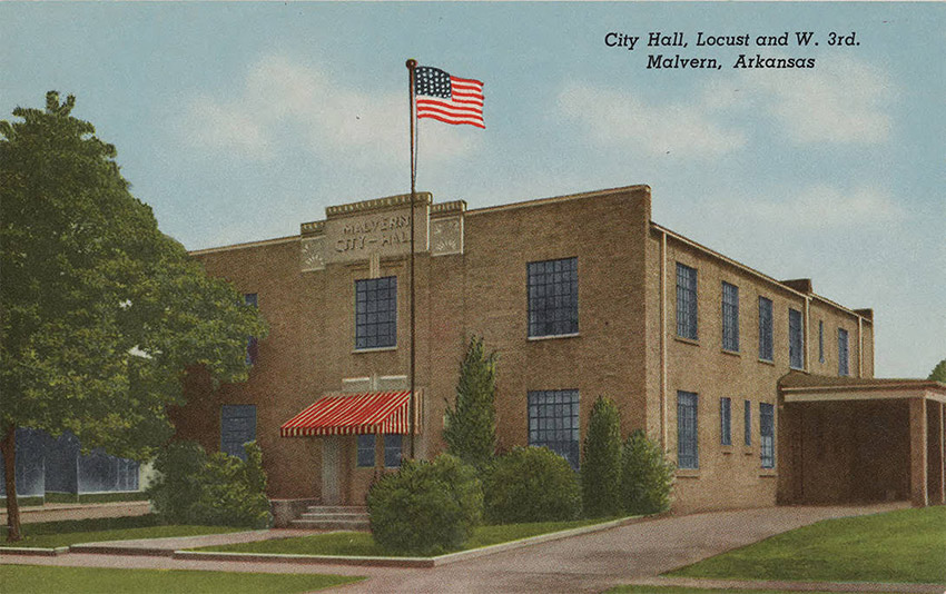 Two story blond brick building with red awning and American flag on pole