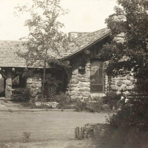 Single-story stone building with porch and trees