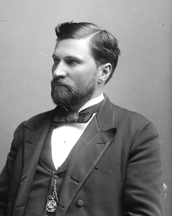 White man in suit with beard and mustache
