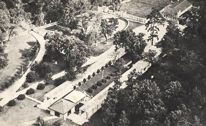 Aerial view of structures and wooded area