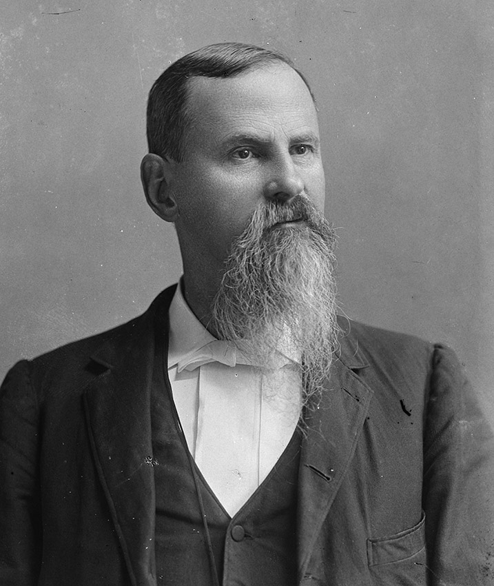 White man in suit with beard and mustache