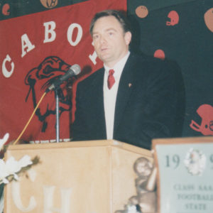 White man speaking into microphone at lectern