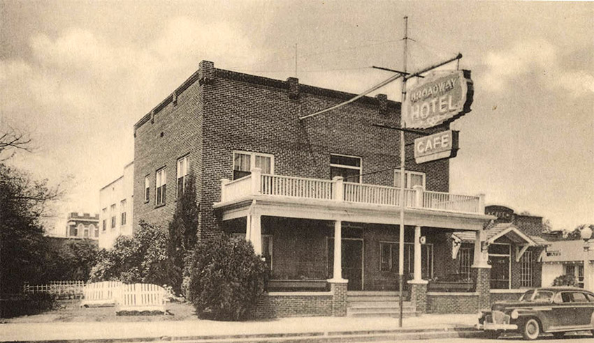 Two story brick building with upper porch and railing "Broadway Hotel and Cafe"