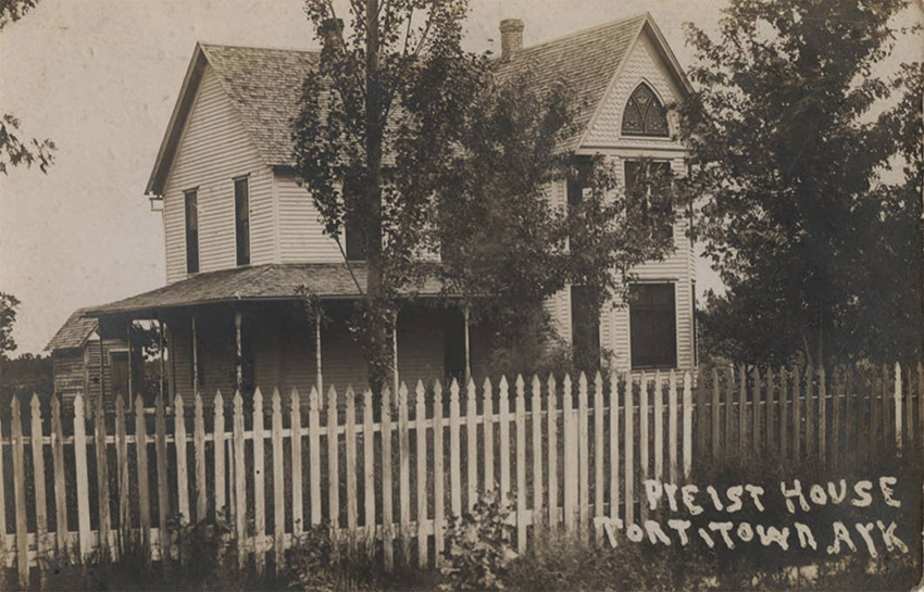 White two-story house behind picket fence