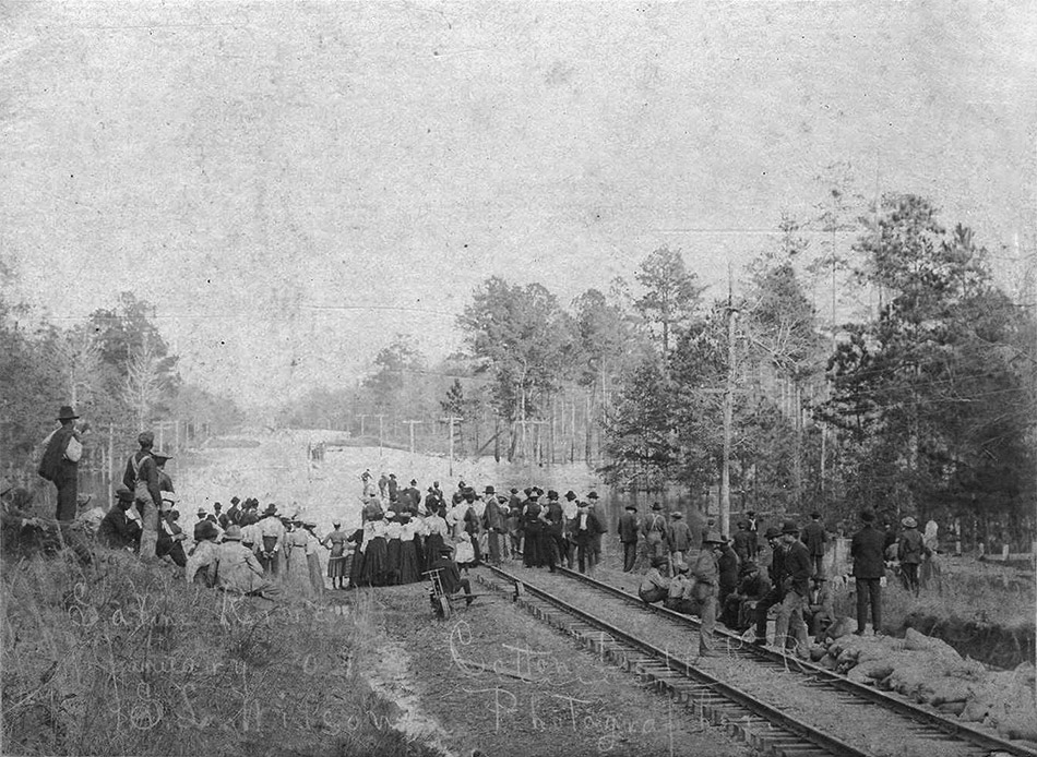 Large group of people standing on railroad tracks looking at flood waters