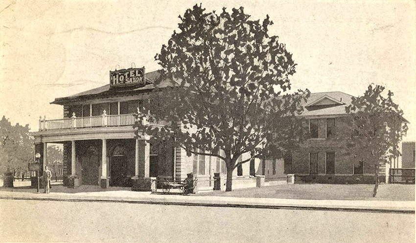 two story brick building with covered entrance with sign saying "Hotel Saxon"