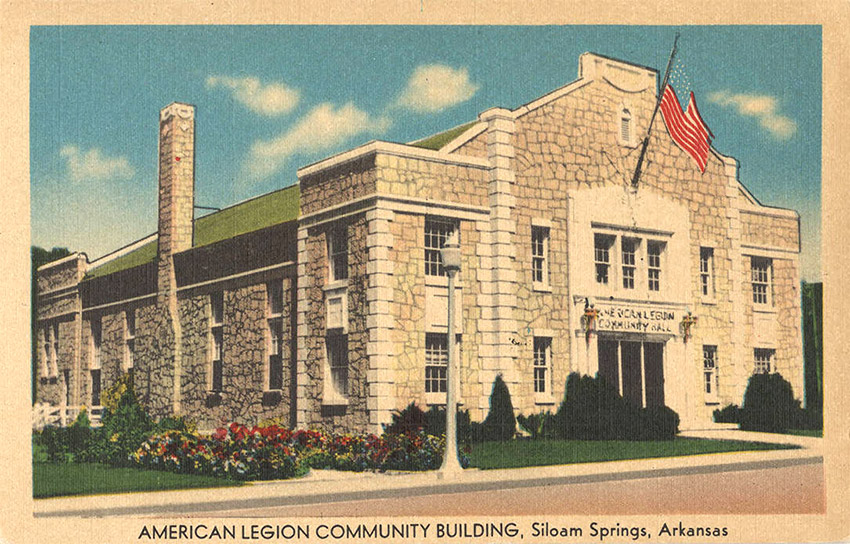 Multistory stone building with large America flag over entrance