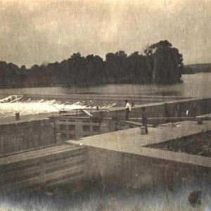 Man standing on large concrete structure while river rushes past