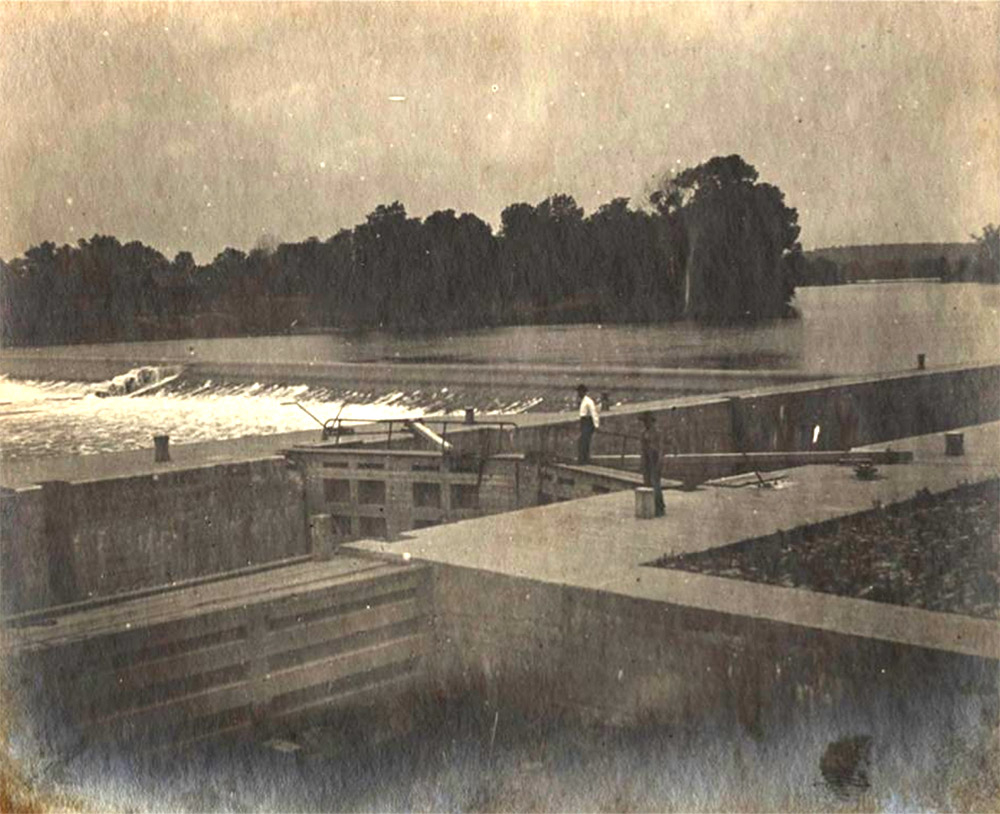Man standing on large concrete structure while river rushes past