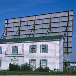 Drive in theater screen from the rear with two story building  in foreground
