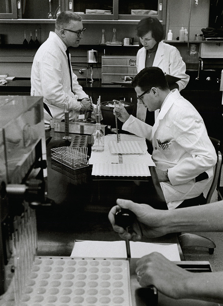 Three white people in research lab wearing white jackets