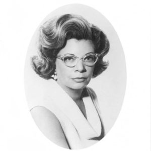 White woman wearing white dress and cat-eye glasses